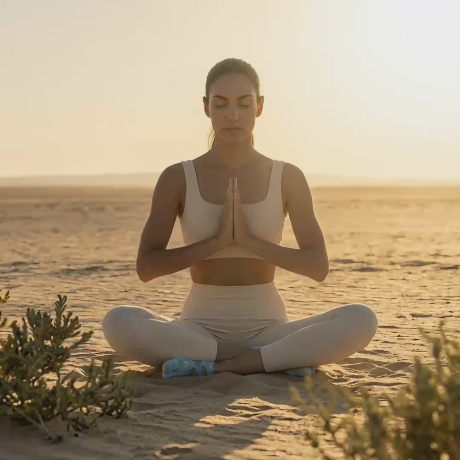 Load video: Mindful yoga movement in a vast desert landscape featuring premium tie-dye functional toe socks by YG Socks, demonstrating fluid control and secure traction on the sand.